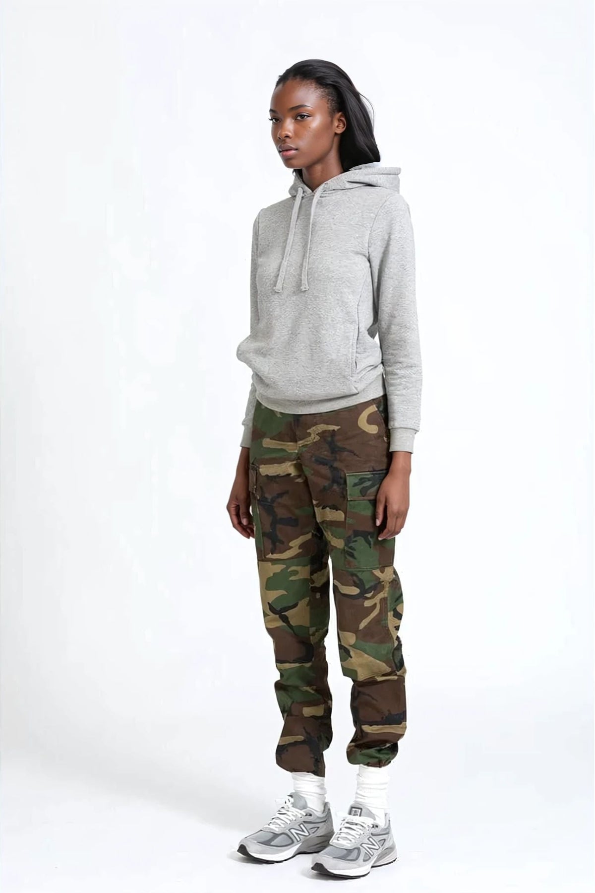 Person wearing a gray hoodie and camouflage pants on a white background