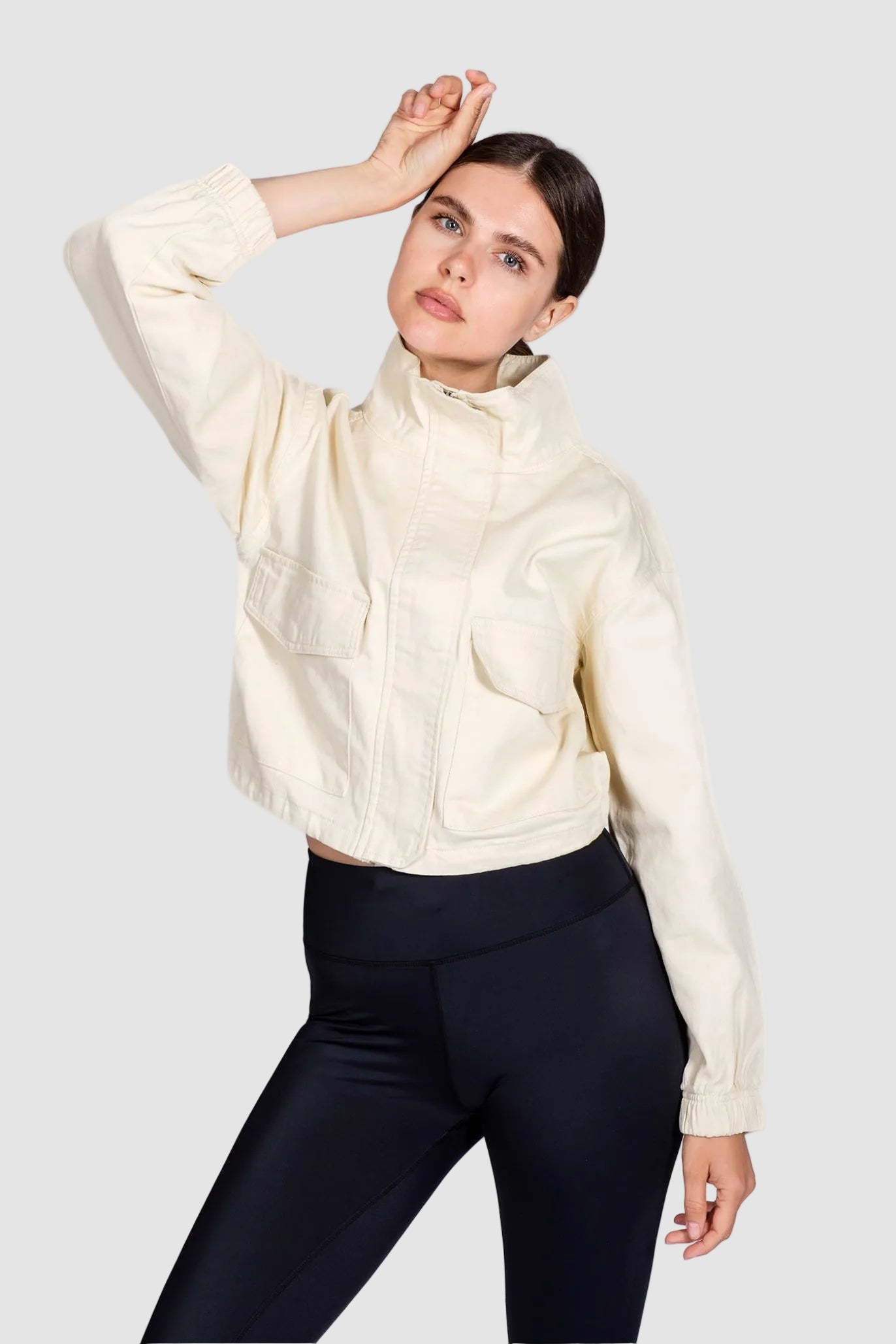 Woman wearing a cream-colored jacket and black pants on a white background
