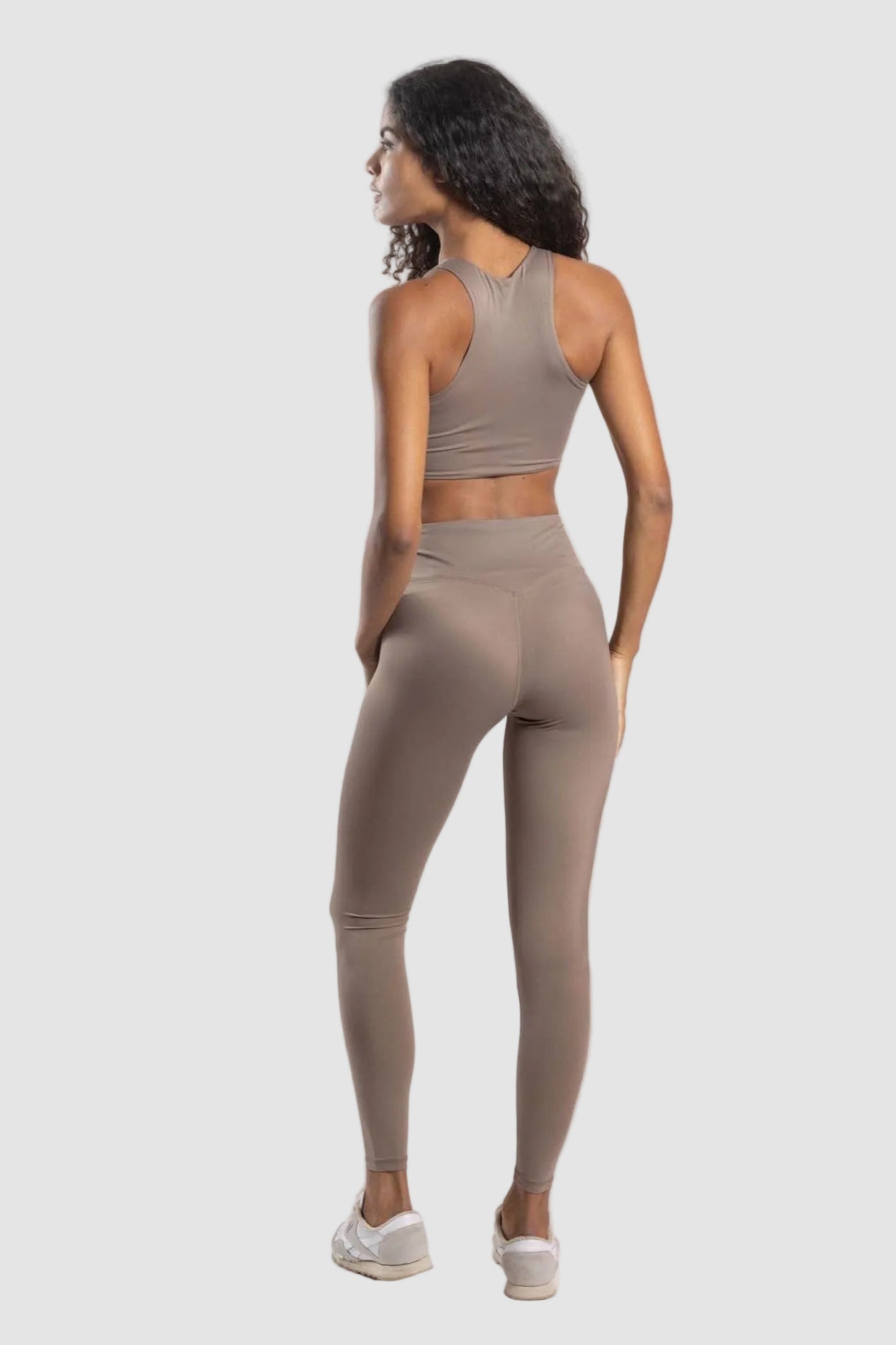 Woman wearing a beige athletic outfit on a white background