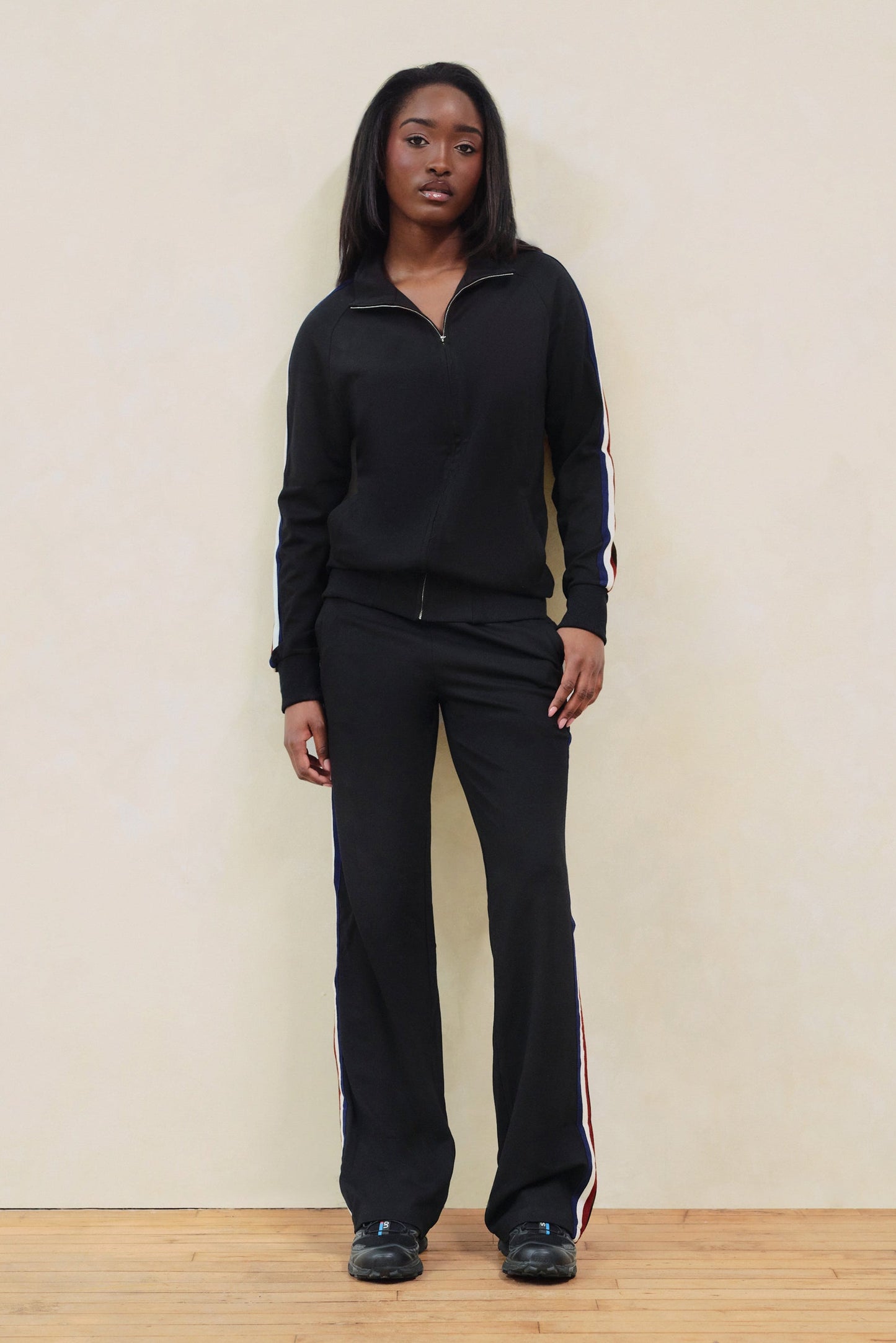 Person wearing a black outfit with a white stripe on a plain background