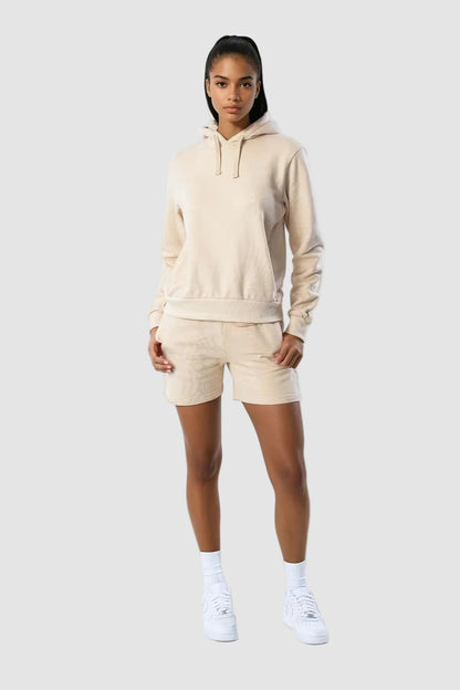Person wearing a beige hoodie and shorts set on a white background