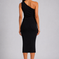 A woman shown from the back wearing a black one-shoulder midi dress and light-colored heeled sandals against a light gray studio background.