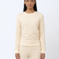 Woman wearing a cream-colored sweater and pants on a white background