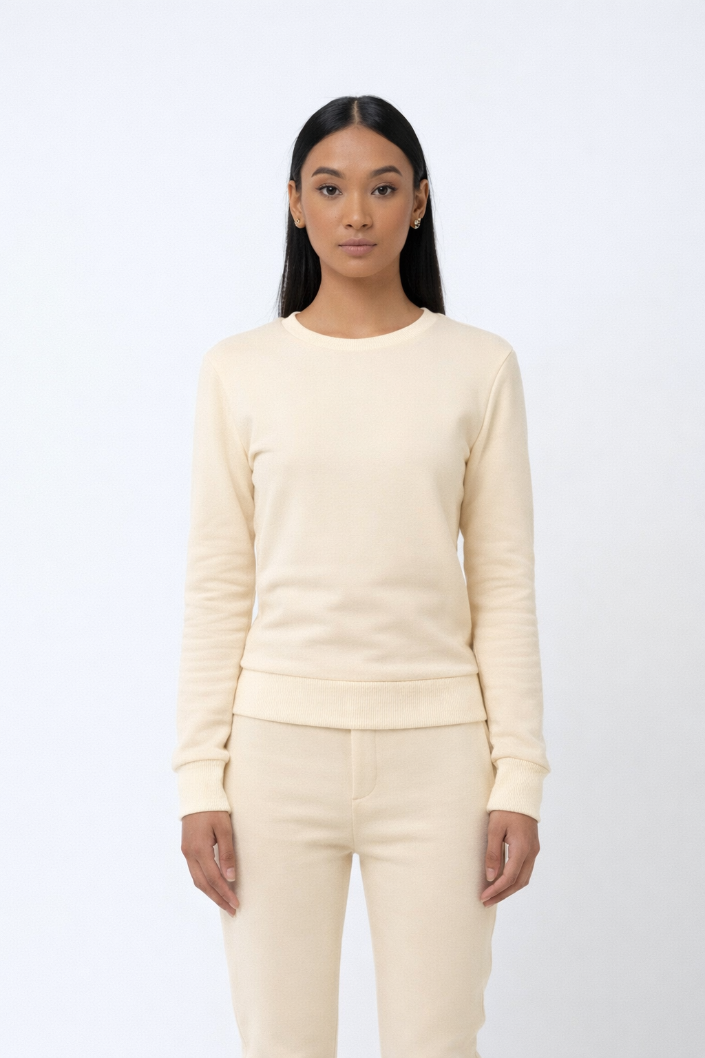 Woman wearing a cream-colored sweater and pants on a white background
