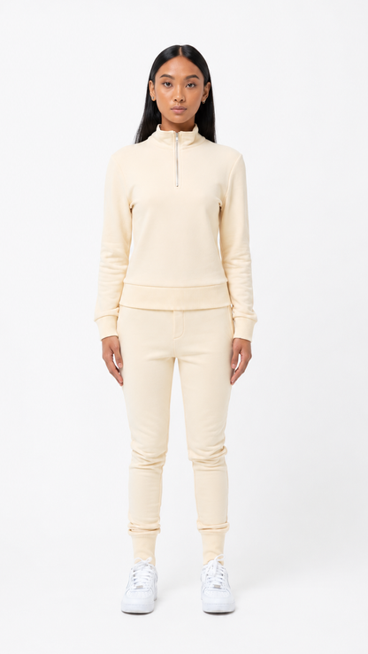 Person wearing a cream-colored tracksuit on a white background