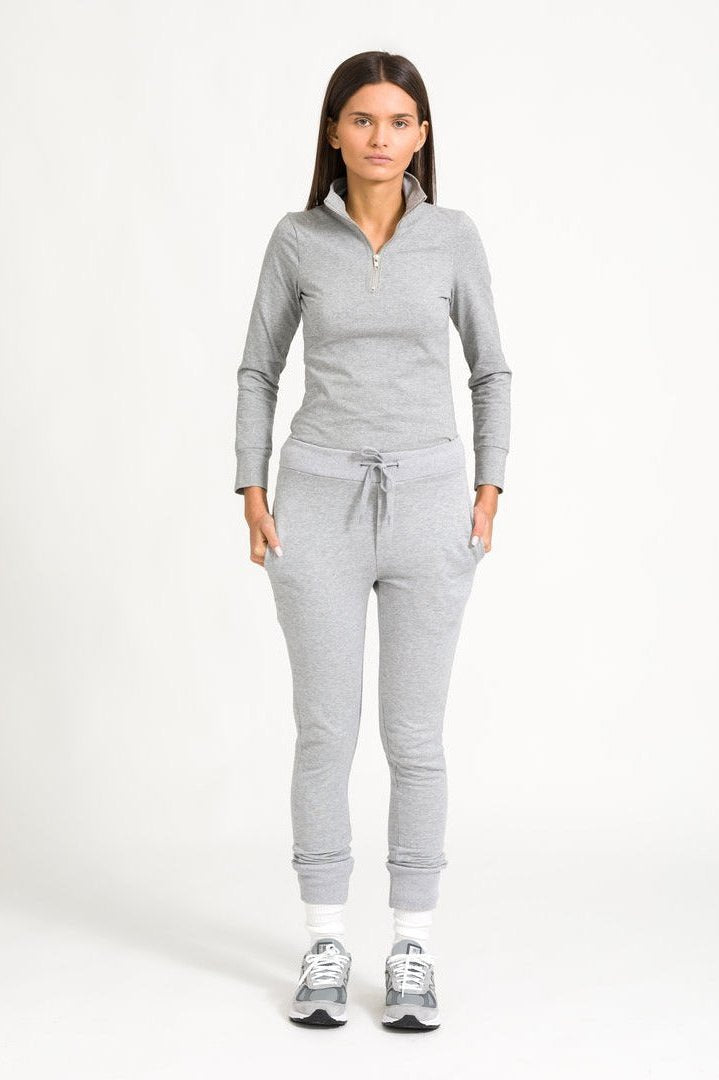 Model in grey zip top against white background.