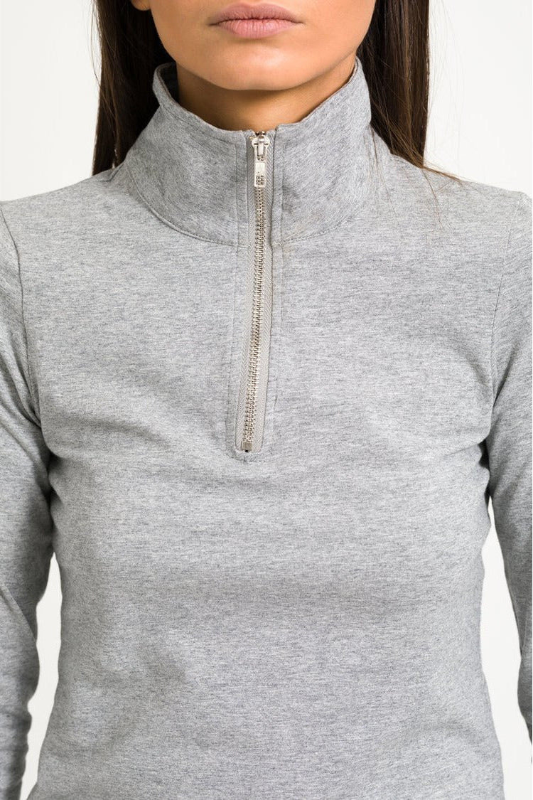 Close up shot of model in half zip top against white background.