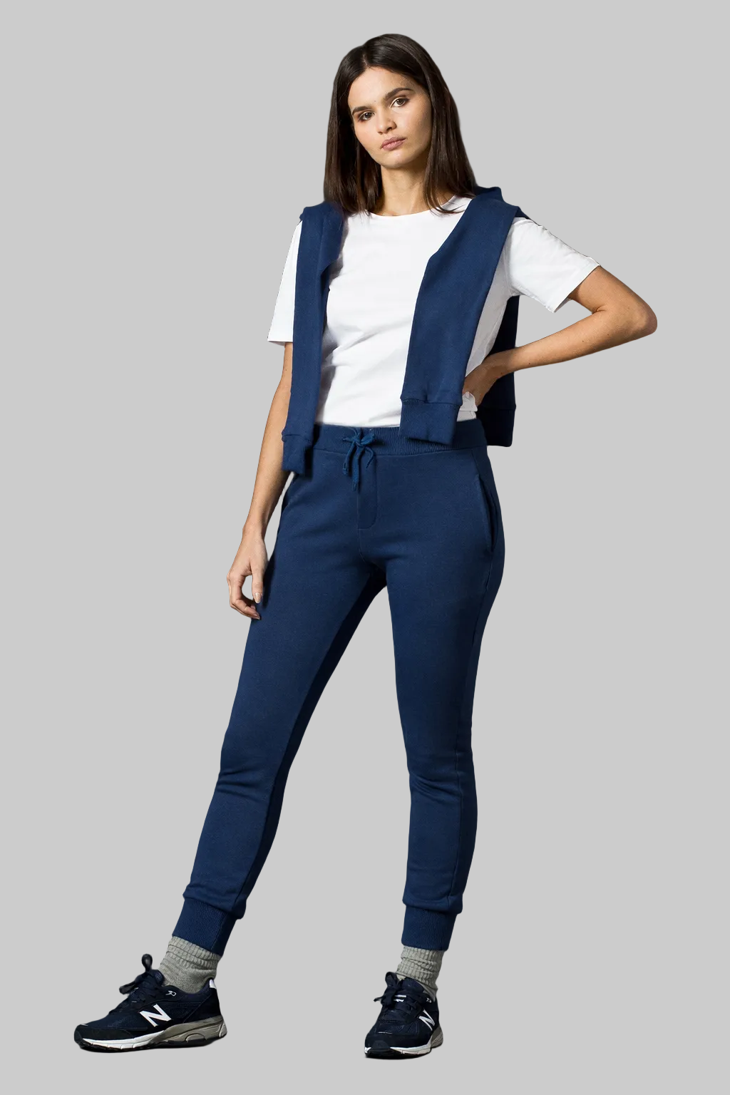 Woman wearing a navy blue vest and pants with a white shirt on a gray background