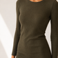 A woman wearing a ribbed long-sleeve crewneck dress in olive green, shown from the chin down against a light neutral background.