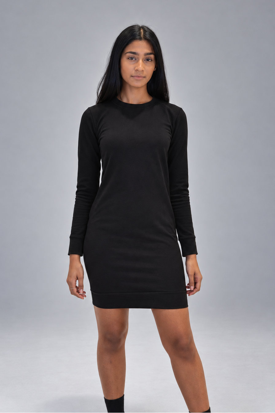 A woman modeling a black long-sleeve crewneck mini dress against a solid gray studio background.