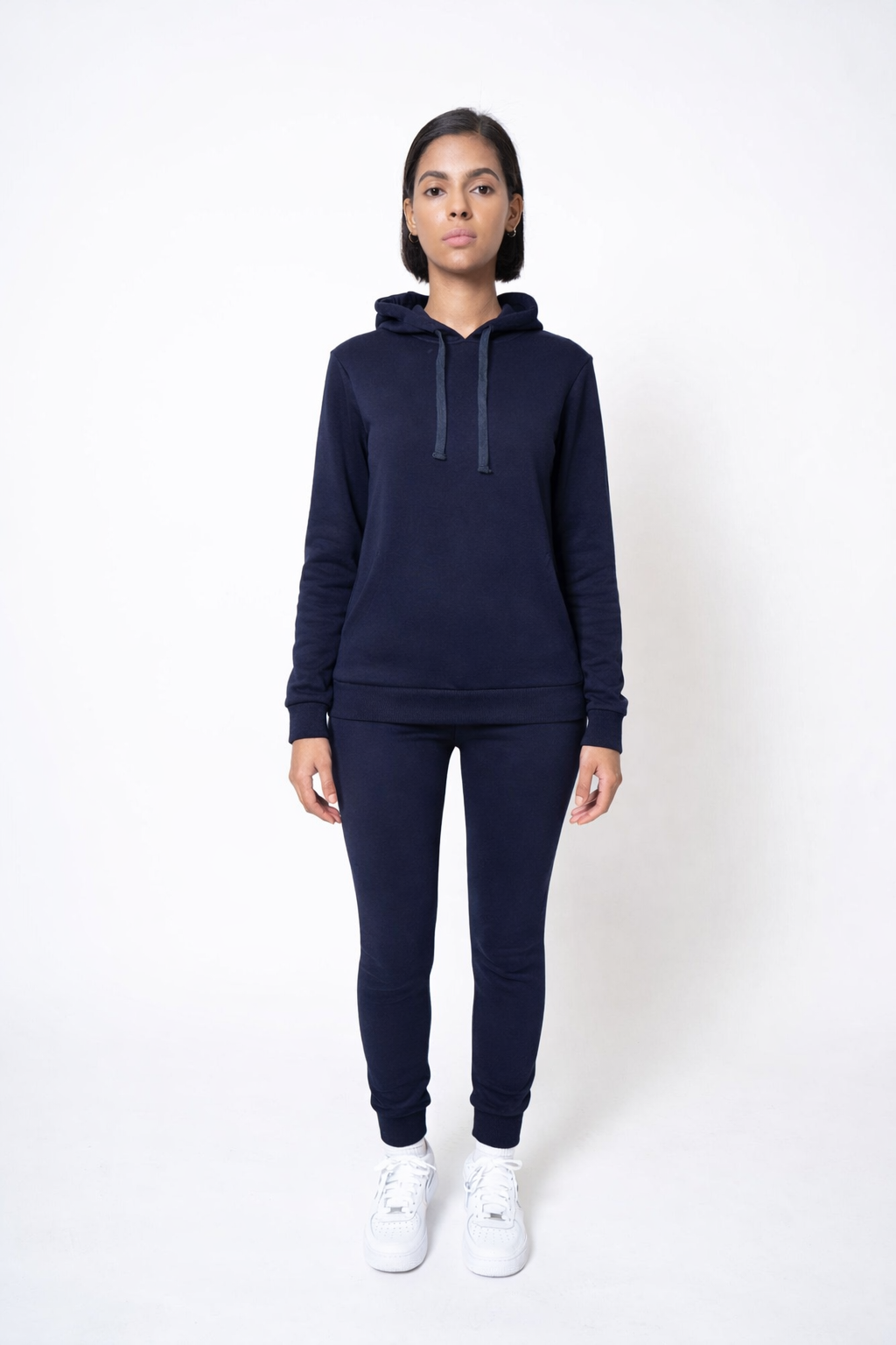 Person wearing a navy blue hoodie and jogger set on a white background
