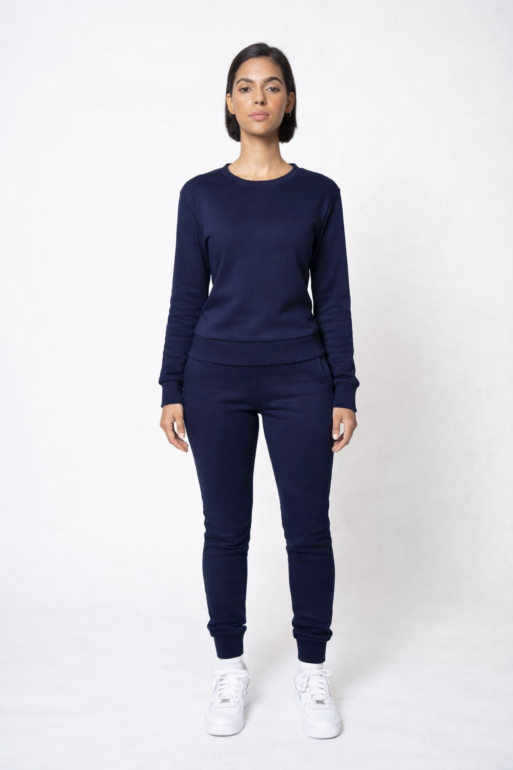 Person wearing a navy blue outfit with white sneakers on a white background