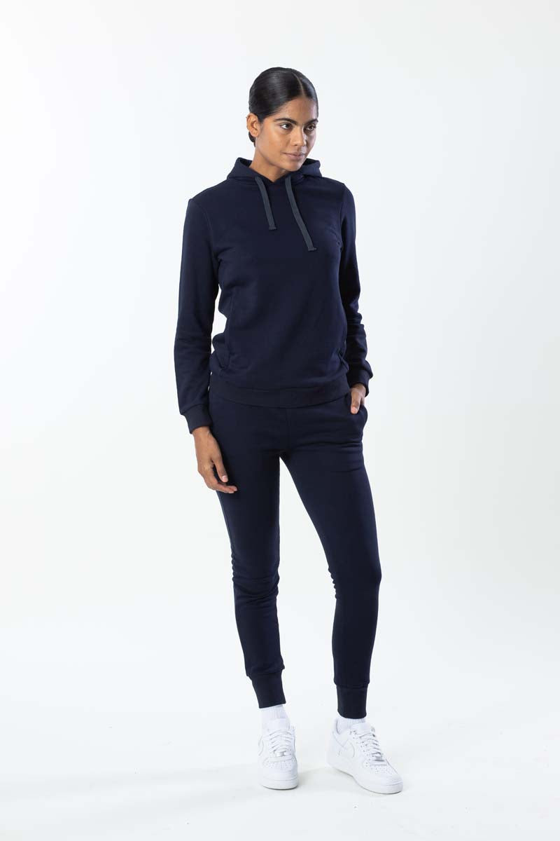 Woman wearing a navy tracksuit with white sneakers on a white background