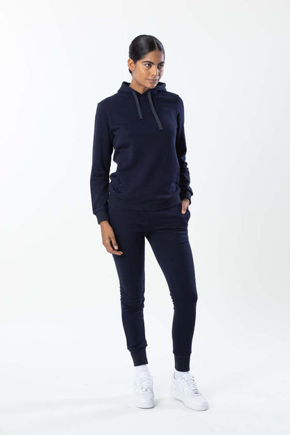 Woman wearing a navy tracksuit with white sneakers on a white background