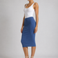 A woman modeling a color-blocked midi skirt with a white top, standing against a light gray studio background.