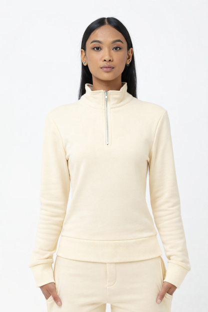 Woman wearing a cream-colored half-zip sweatshirt on a white background