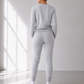 Person wearing a gray tracksuit standing in a well-lit room with a window.