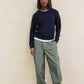 Person wearing a navy sweater and green cargo pants against a beige wall.