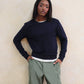 Person wearing a navy sweater and green cargo pants against a beige wall