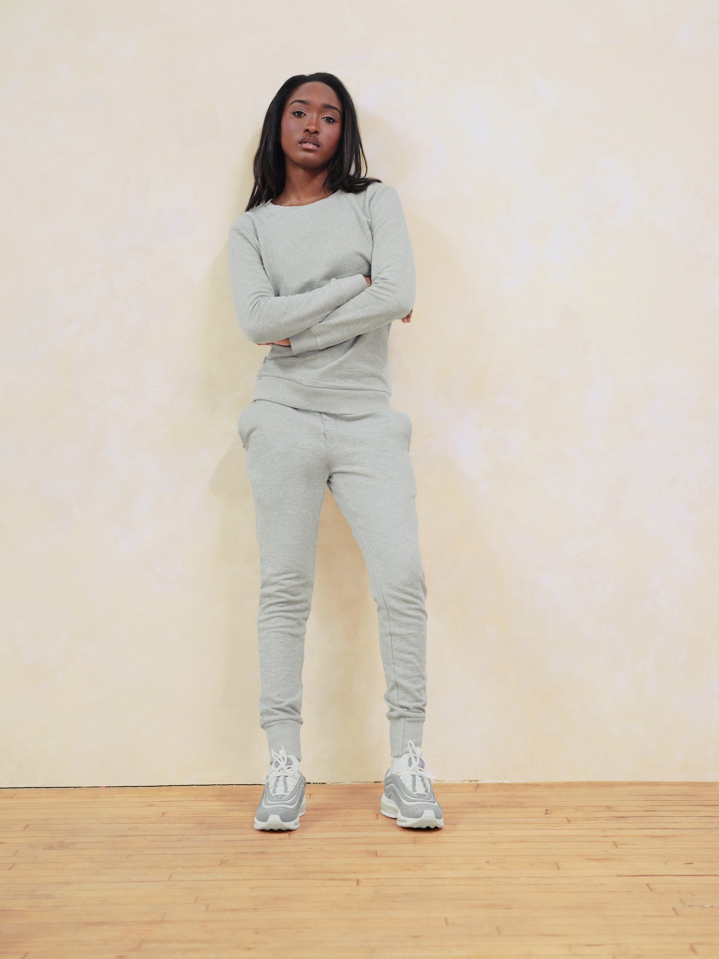 Person wearing a gray tracksuit standing against a plain background