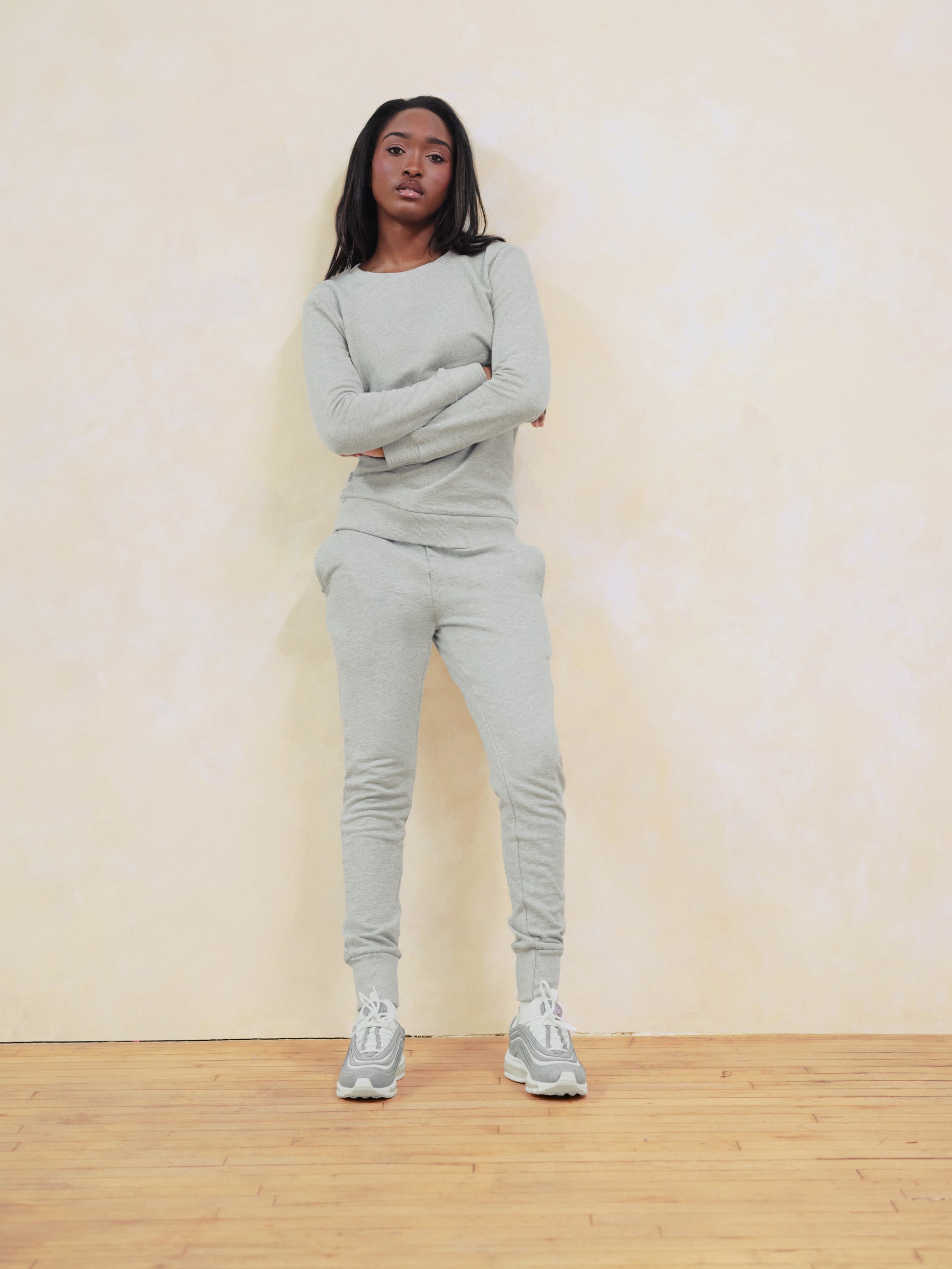 Person wearing a gray tracksuit standing against a plain background