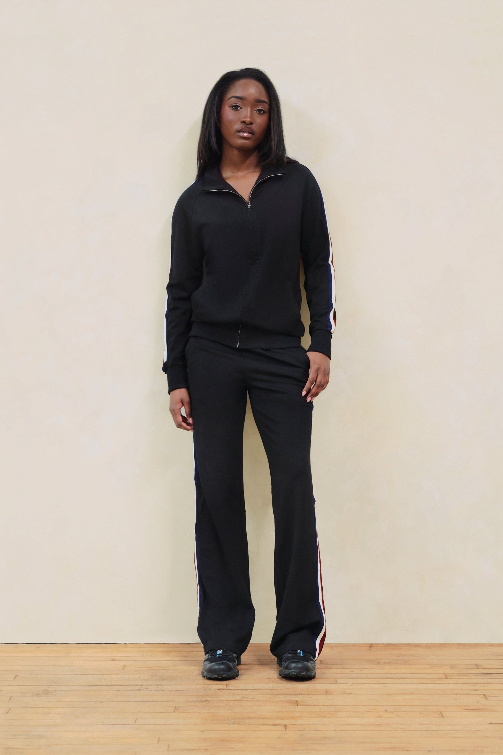 Person wearing a black outfit with a white stripe on a plain background