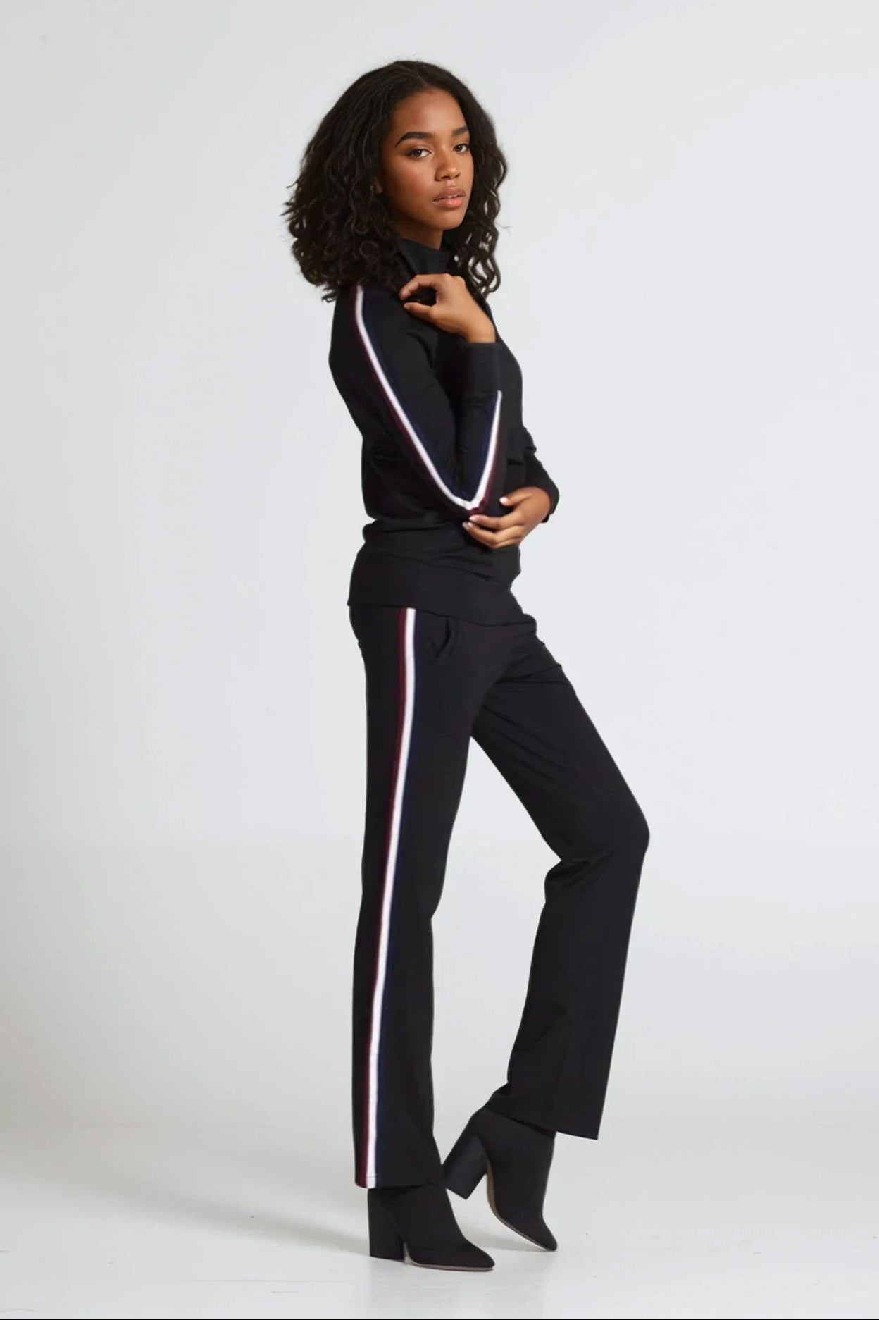 Woman wearing a black outfit with white stripes on a white background