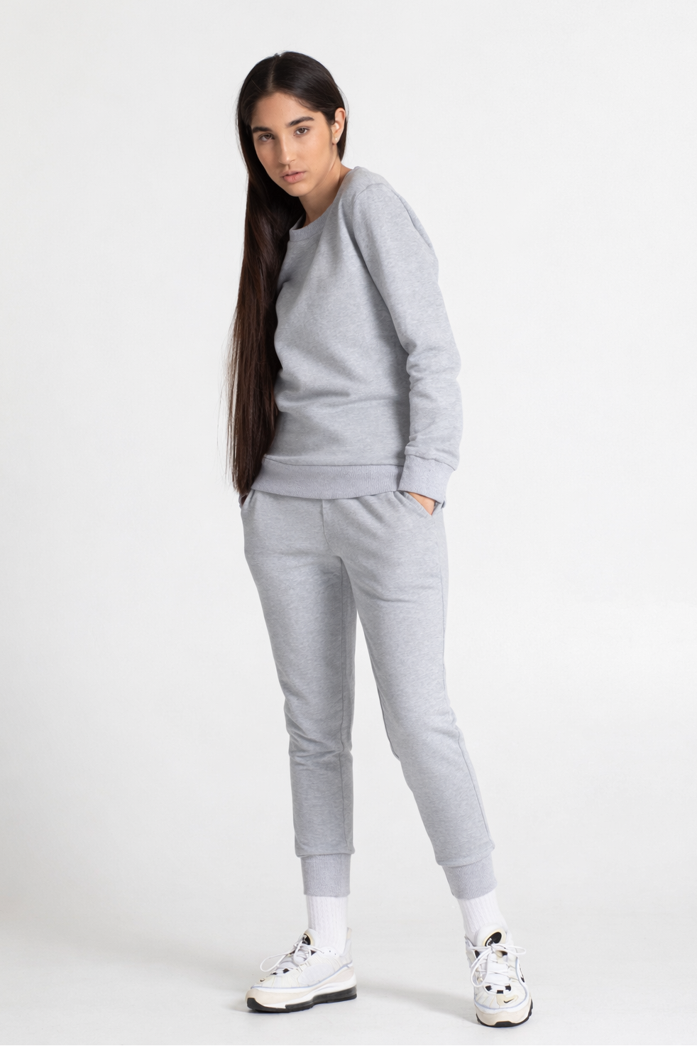Woman wearing a grey sweatshirt and sweatpant on a white background