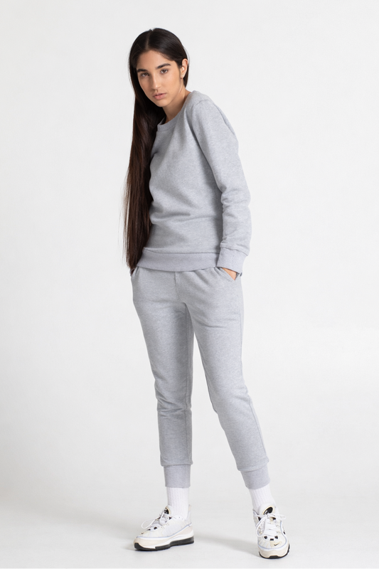 Woman wearing a grey sweatshirt and sweatpant on a white background