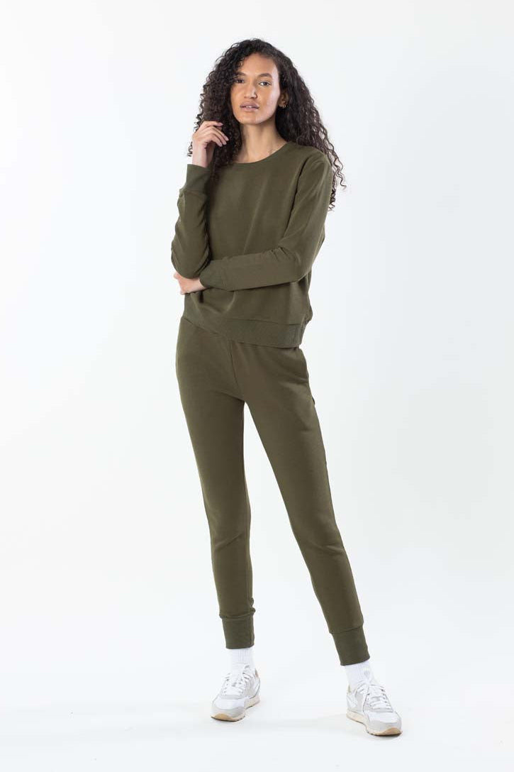Woman wearing an olive green tracksuit on a white background
