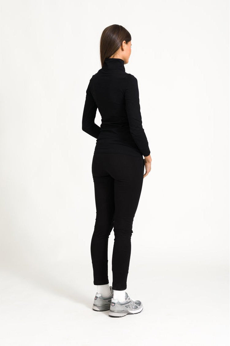 Model back view of black zip top outfit against a white background.