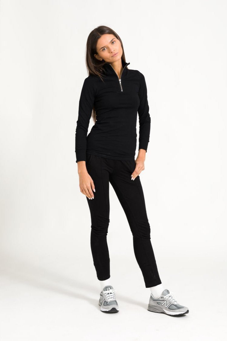 Model in black zip top outfit against a white background.