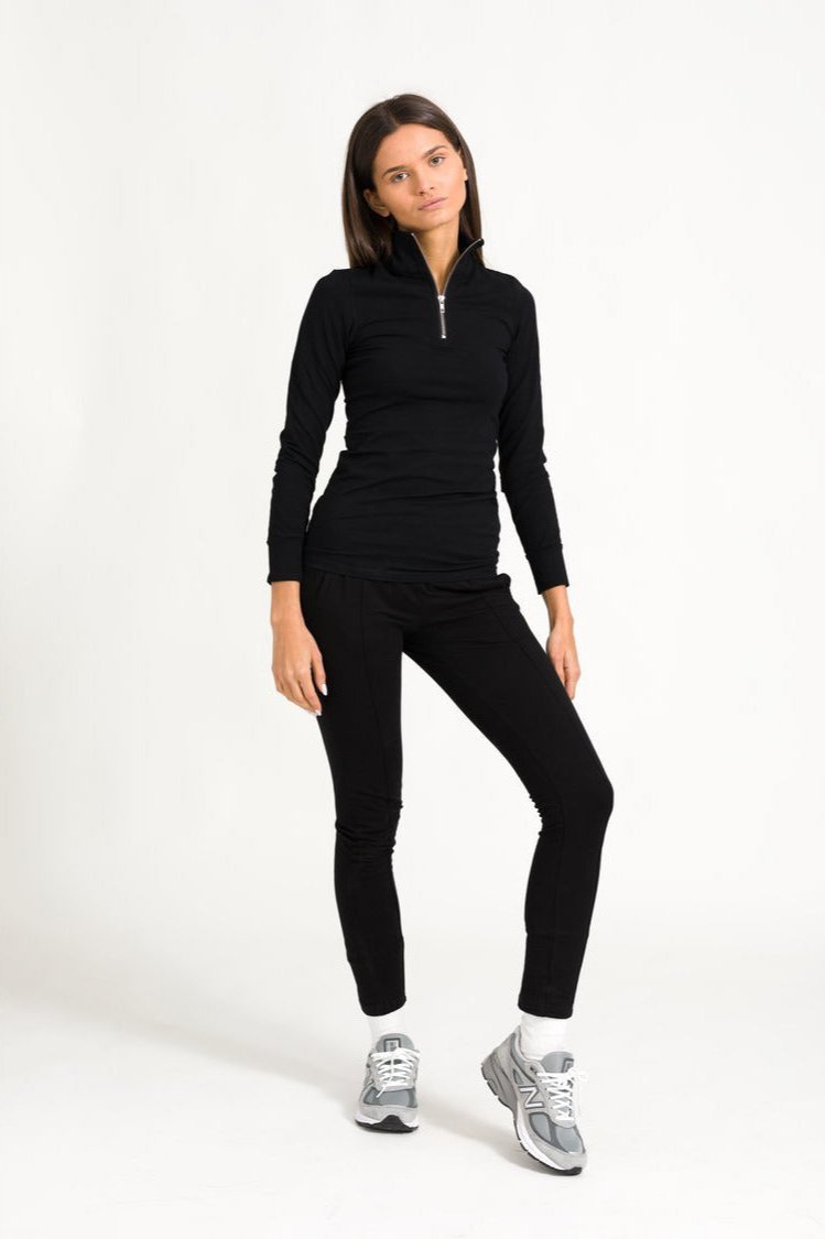 Model in black zip top and black track pant outfit.